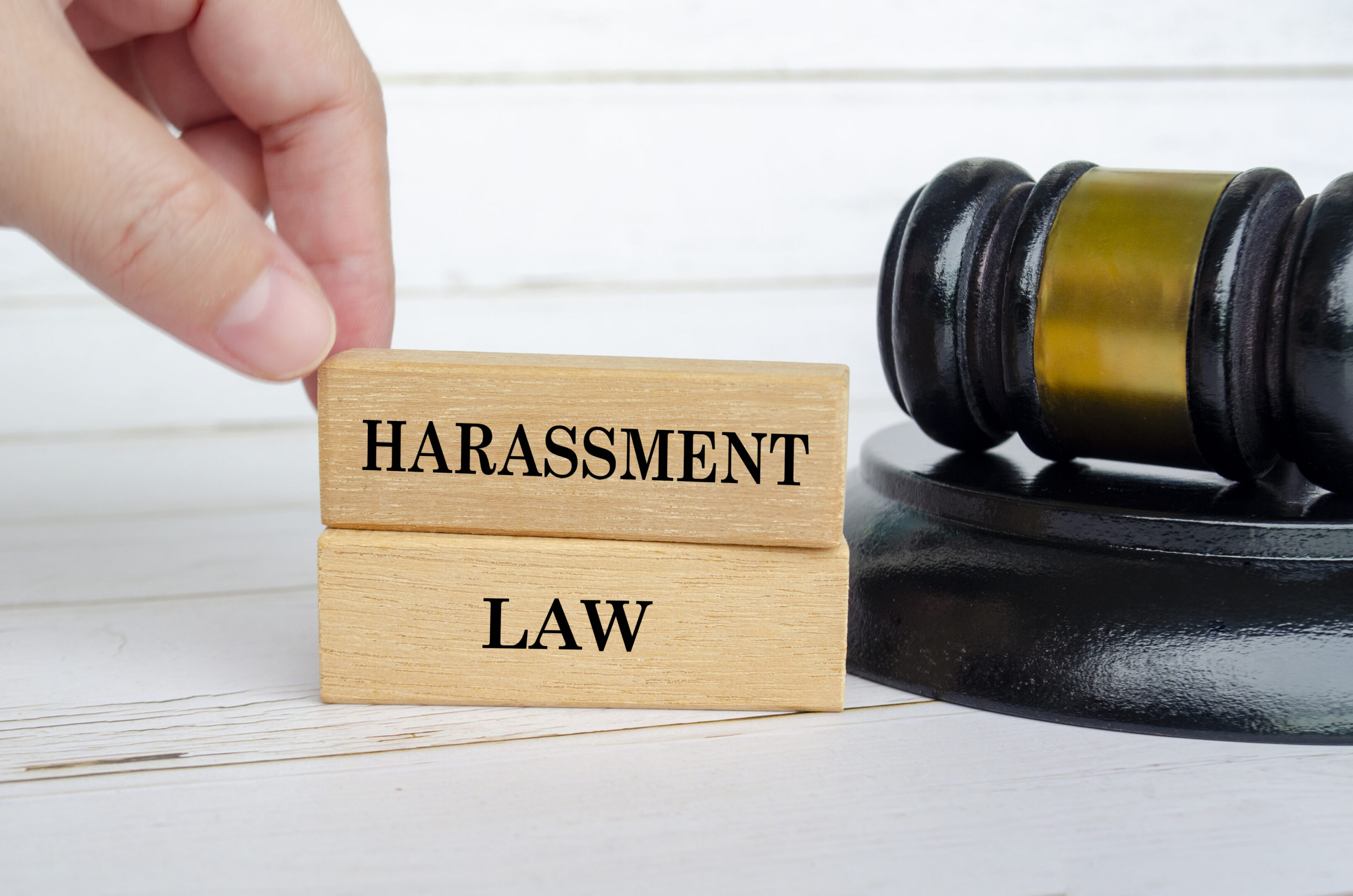 Hand holding wooden blocks with Harassment Law text. Law and protection against harassment concept.