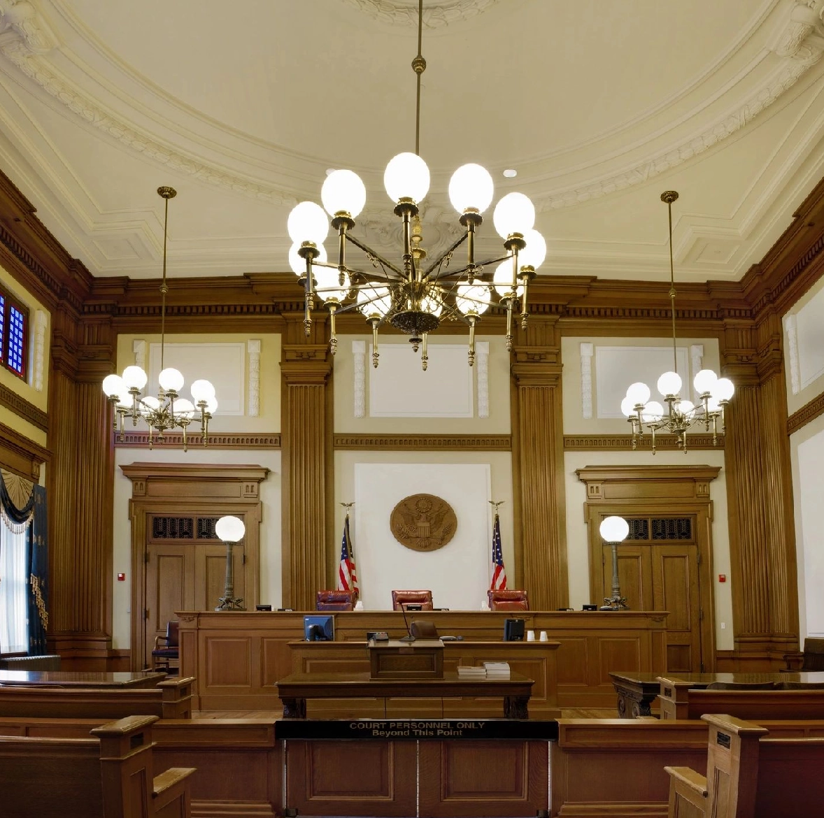 Ornate courtroom, judge's bench, American flags.